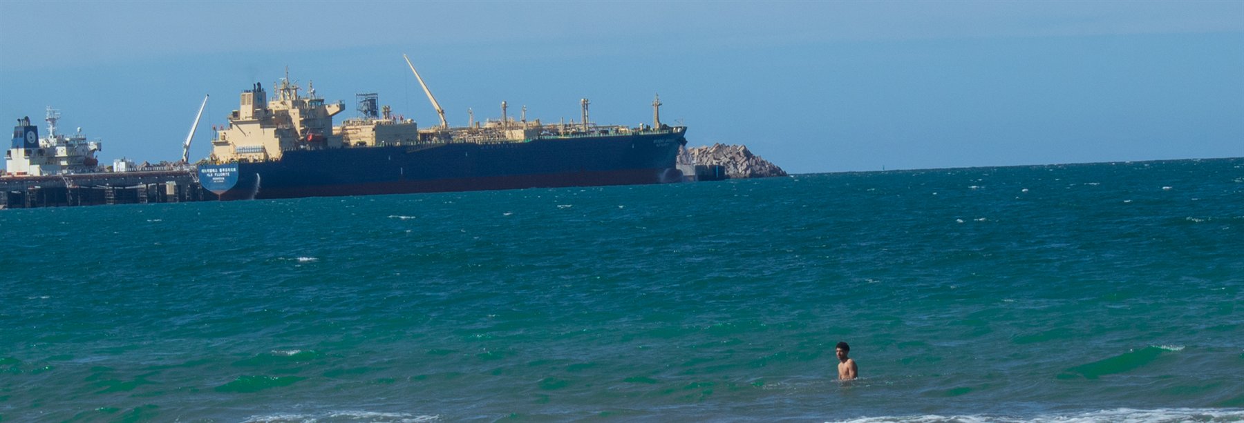 A cargo ship beyond turquoise water at the harbor