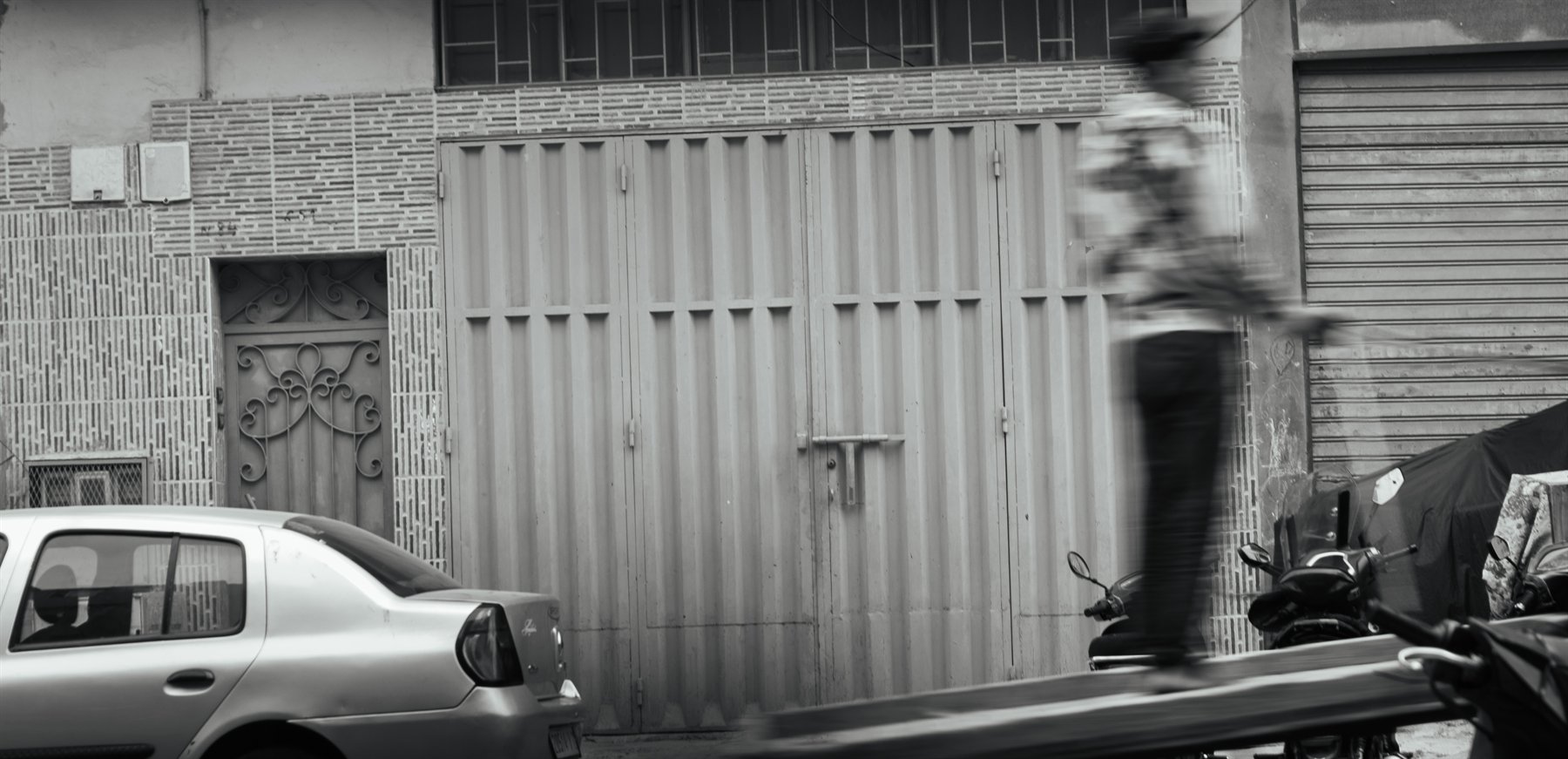 A blurred pedestrian crossing a monochrome city street